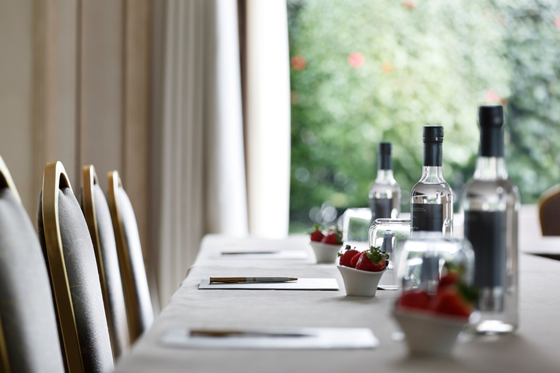 A close-up of a table laid out for a meeting, with notepads, pens, water and fruit