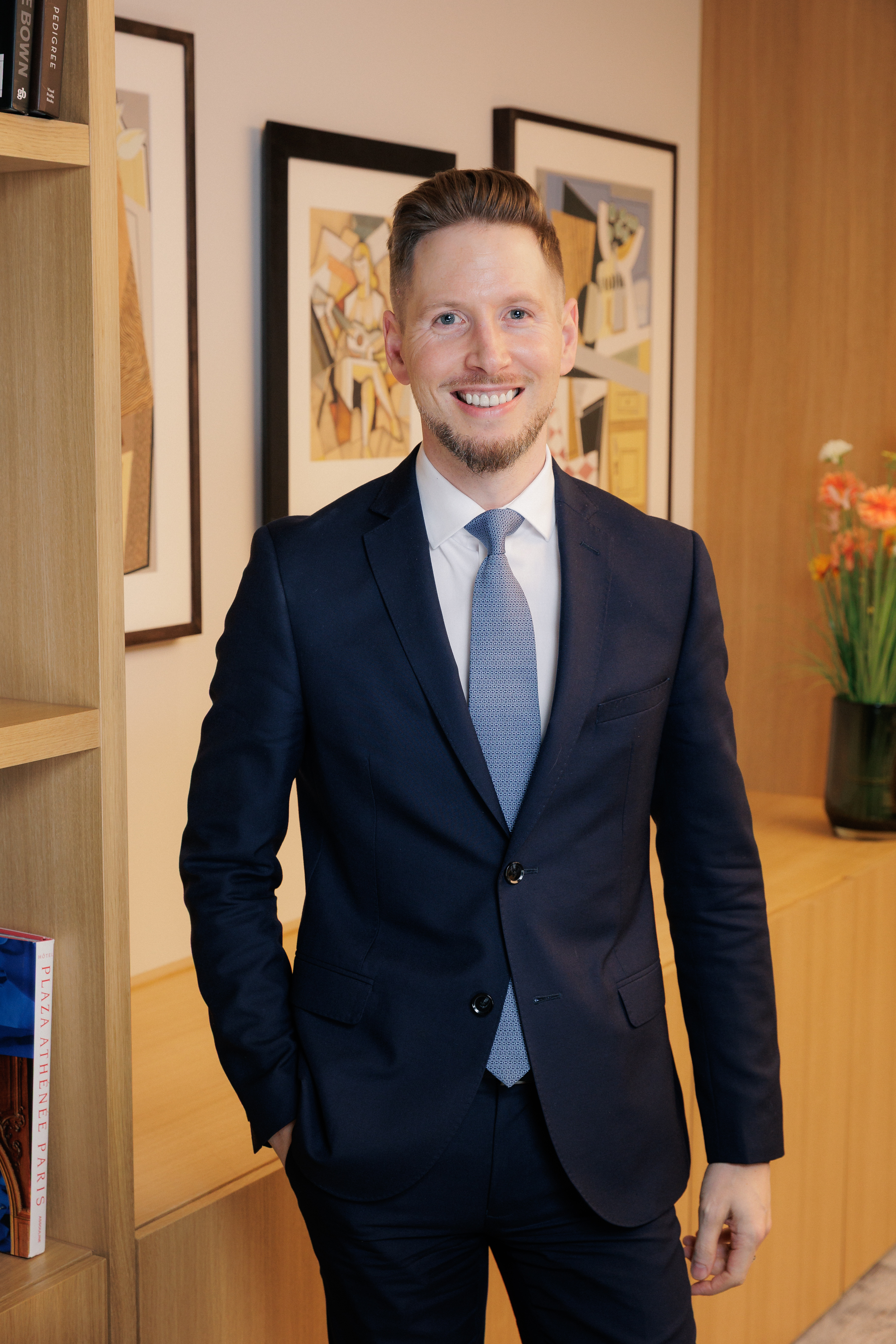 Portrait of Chris Fairless with picture frames hanging in background