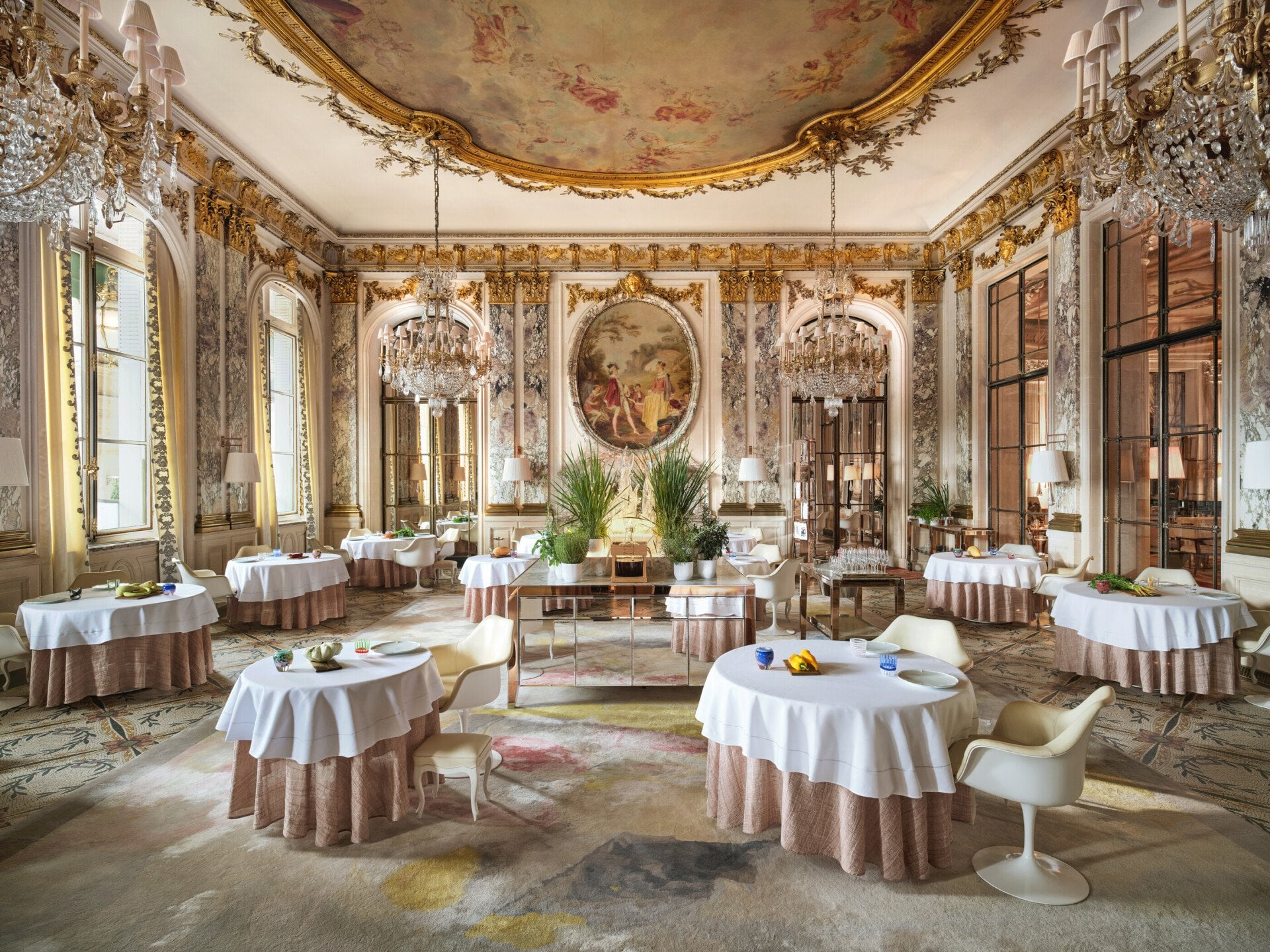 Grande vue du Restaurant le Meurice Alain Ducasse avec les meubles, les lustres, les plantes et la nourriture sur les tables, au Meurice, Paris