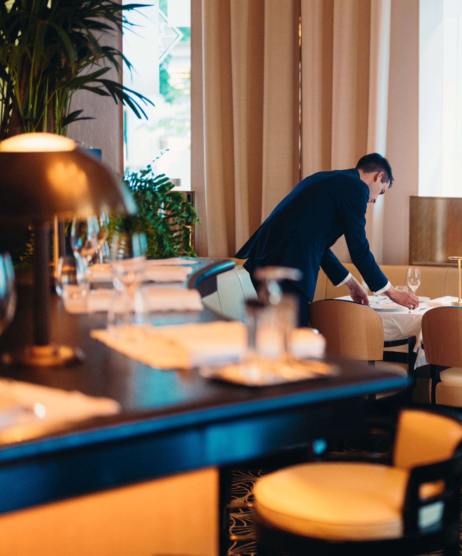 Maitre d'Hotel of Le Relais Plaza drawning up a table with bar counter at the forefront, at Hotel Plaza Athénée, Paris