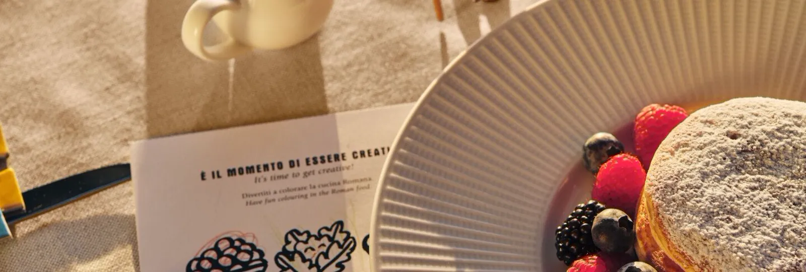 Colazione per bambini a base di pancake, con giocattoli e un libro da colorare