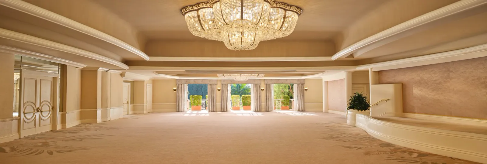 Empty elegant ballroom with chandelier and large windows, inviting a formal event