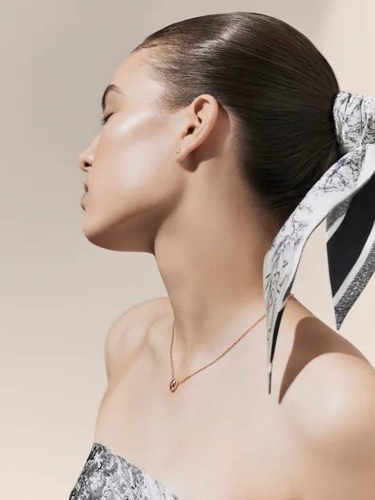 L’iconographie du spa Dior Spa Plaza Athénée. Ici, une mannequin à la peau claire pose la tête penchée vers sa droite, accessoirisée d’une bande de tête en toile de jouy et d’un court collier en or rose.