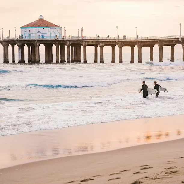 Two surfers heading to the sea at Manhattan Beach for a surfing session