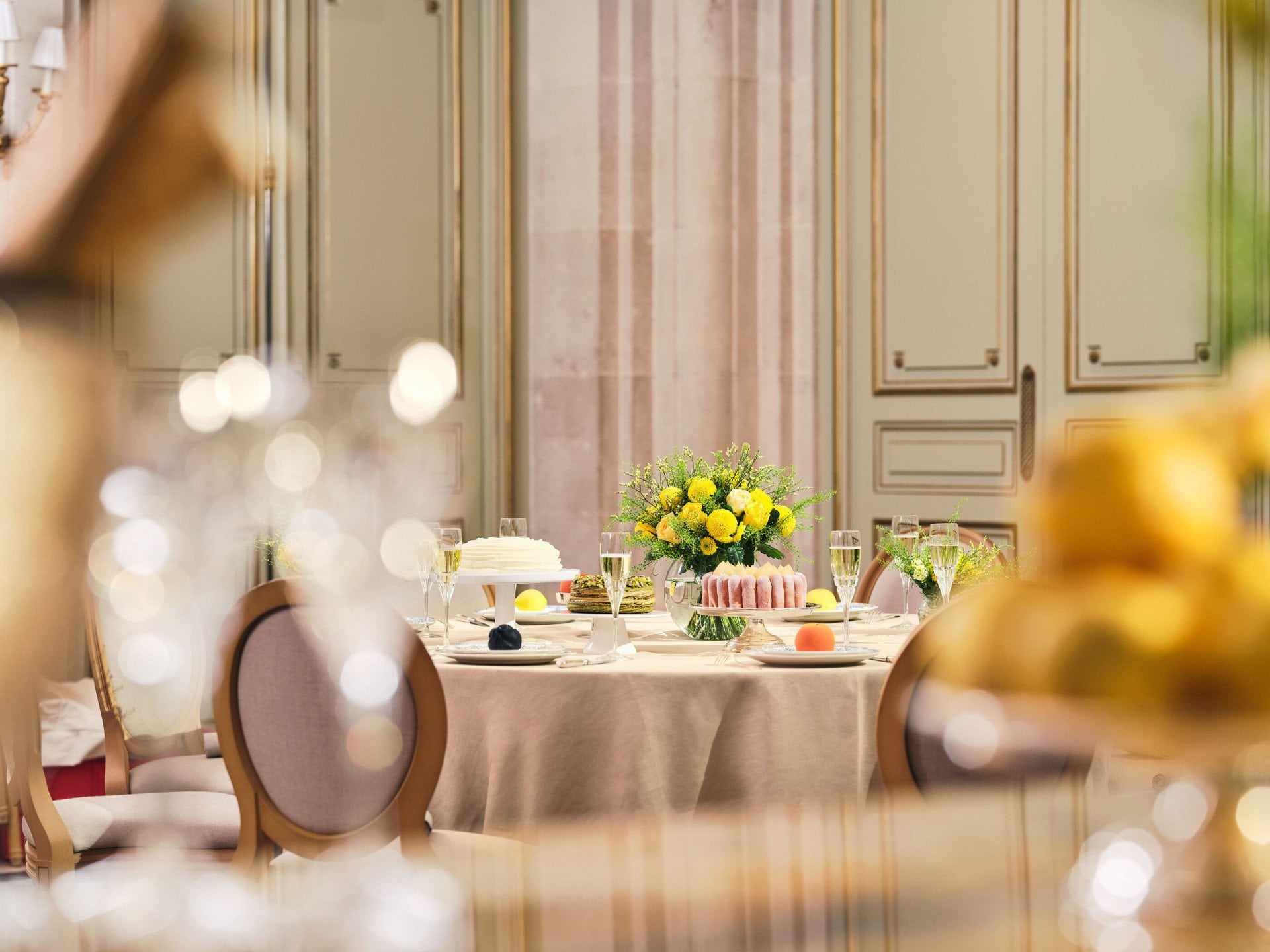 Large view of the table with flower arrangement, champagne glasses, cakes and fruits in the Salon Tuileries, at Le Meurice, Paris - Dorchester Collection