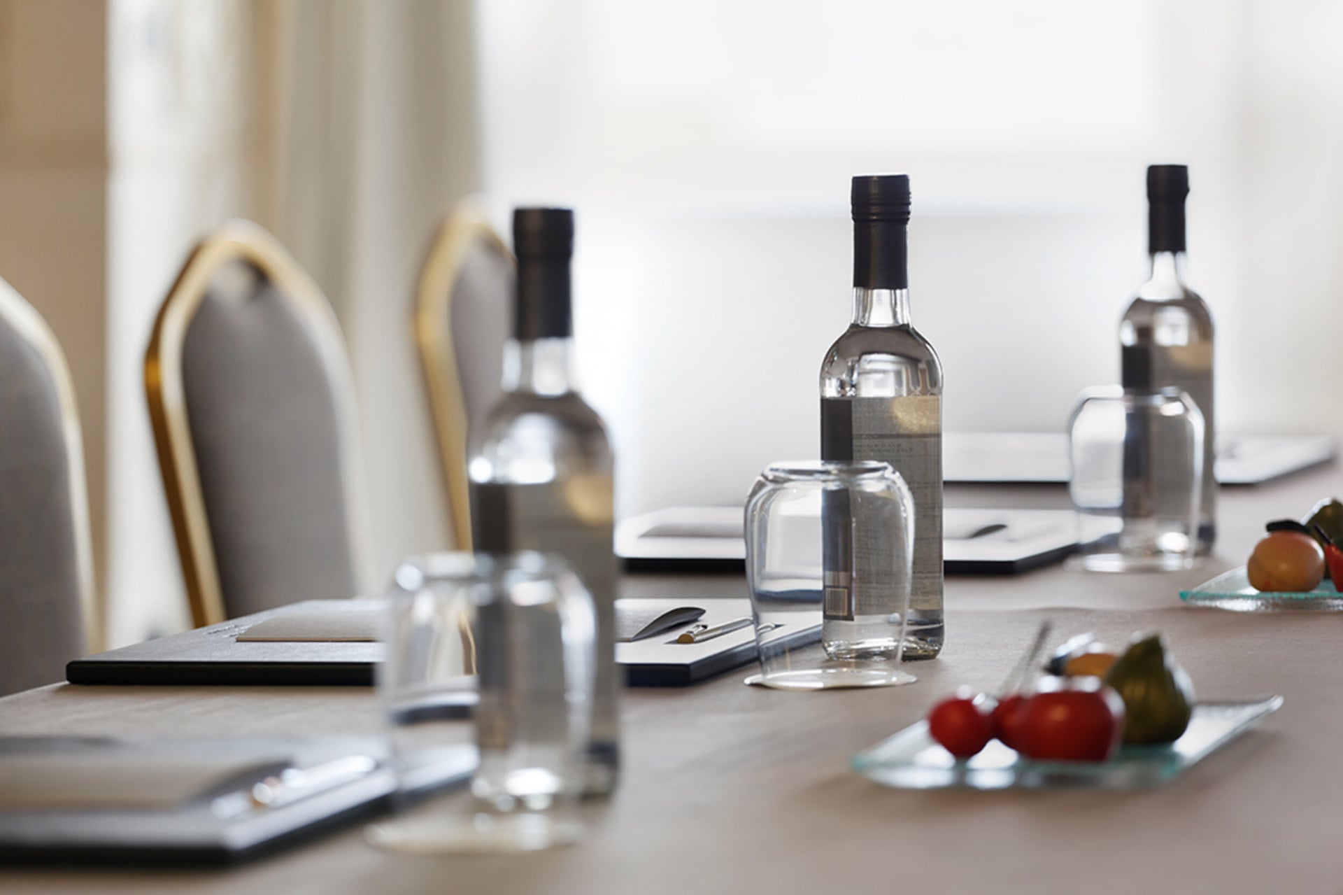 a close-up of a table in a meeting room with water, fruit and notepads