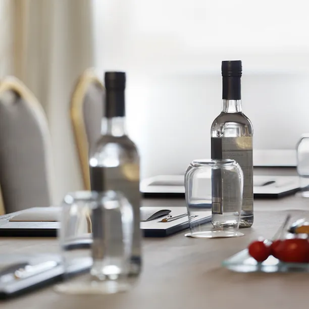 a close-up of a table in a meeting room with water, fruit and notepads