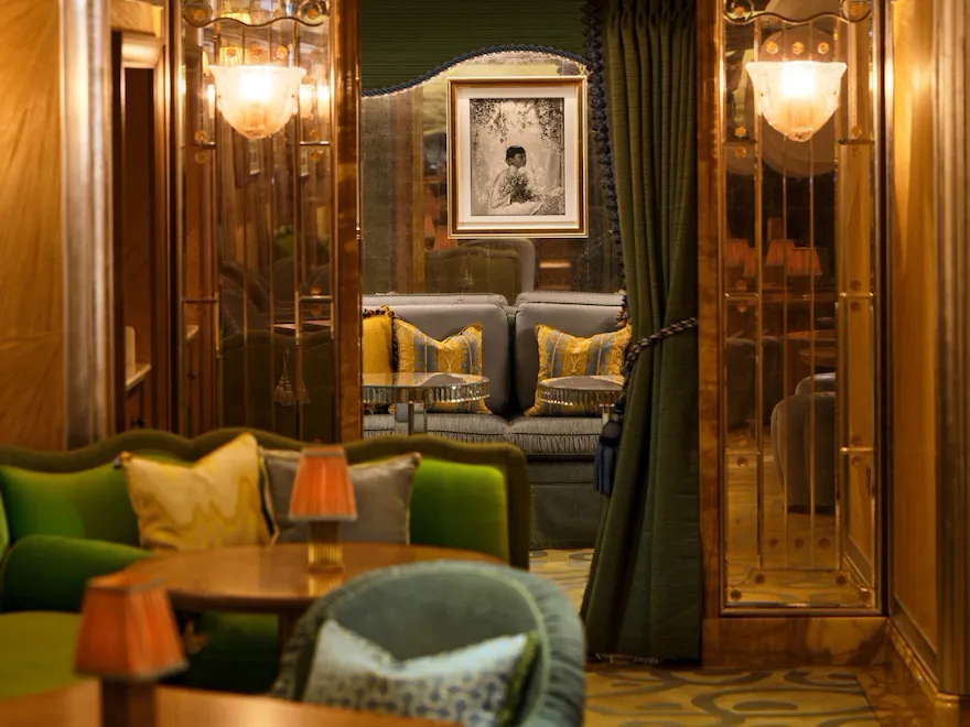 The Snug at The Vesper Bar, a secluded seating area framed by rich wood panelling, green seating and elegant draped curtains.