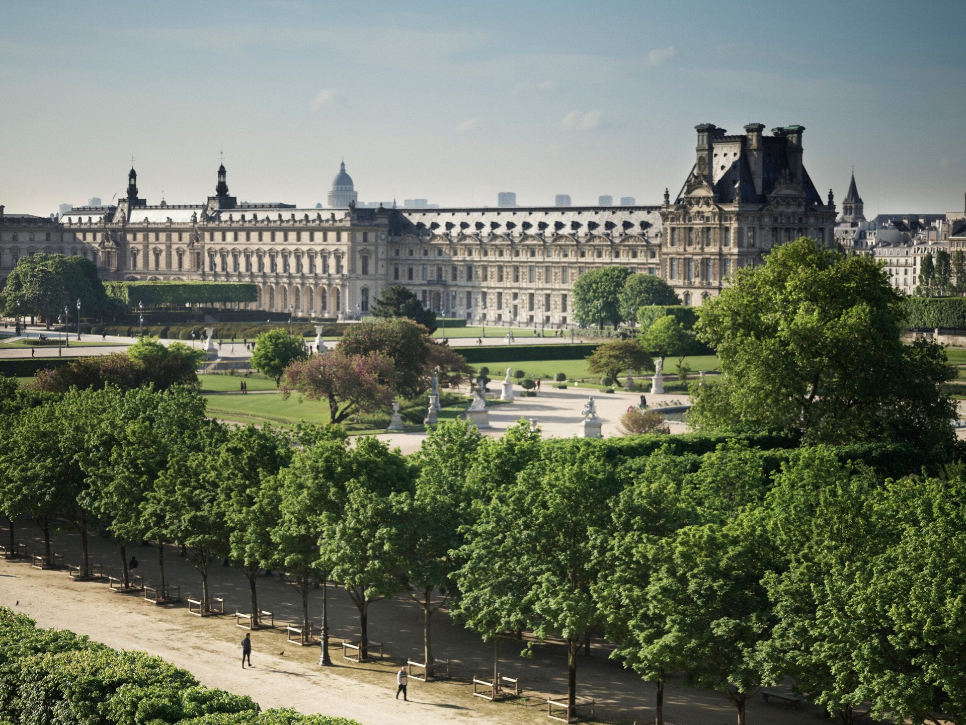 Vista de lombo para o jardim das Tulherias, com a luz do dia e uma avenida de árvores. Au Meurice, Paris.