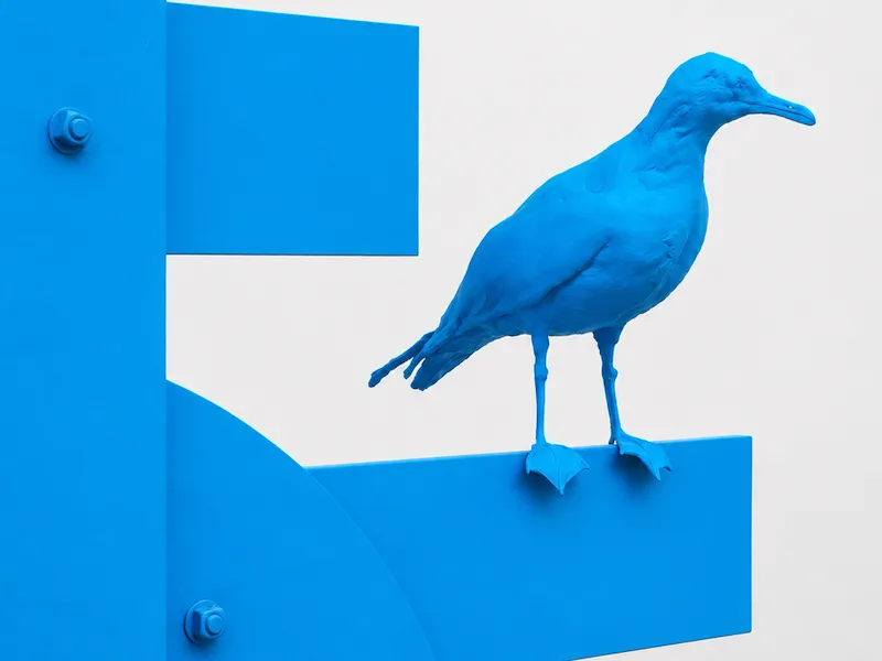 Artist, Nathan Mabry's blue sculpture of a bird perched on a structure.