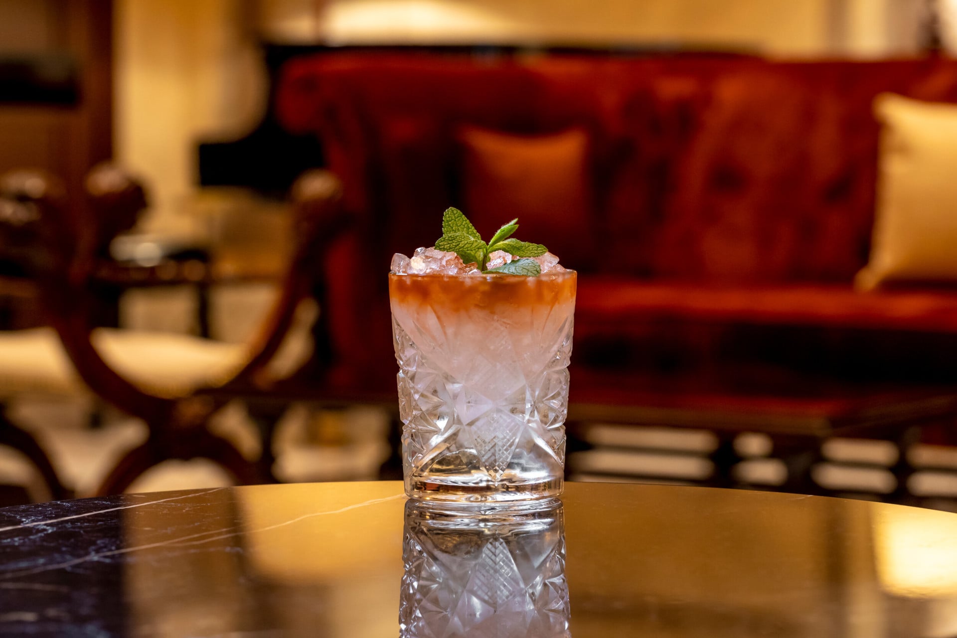Cocktail in bicchiere da whisky decorato con foglie di menta su di un tavolo a la Libreria, Hotel Eden Roma