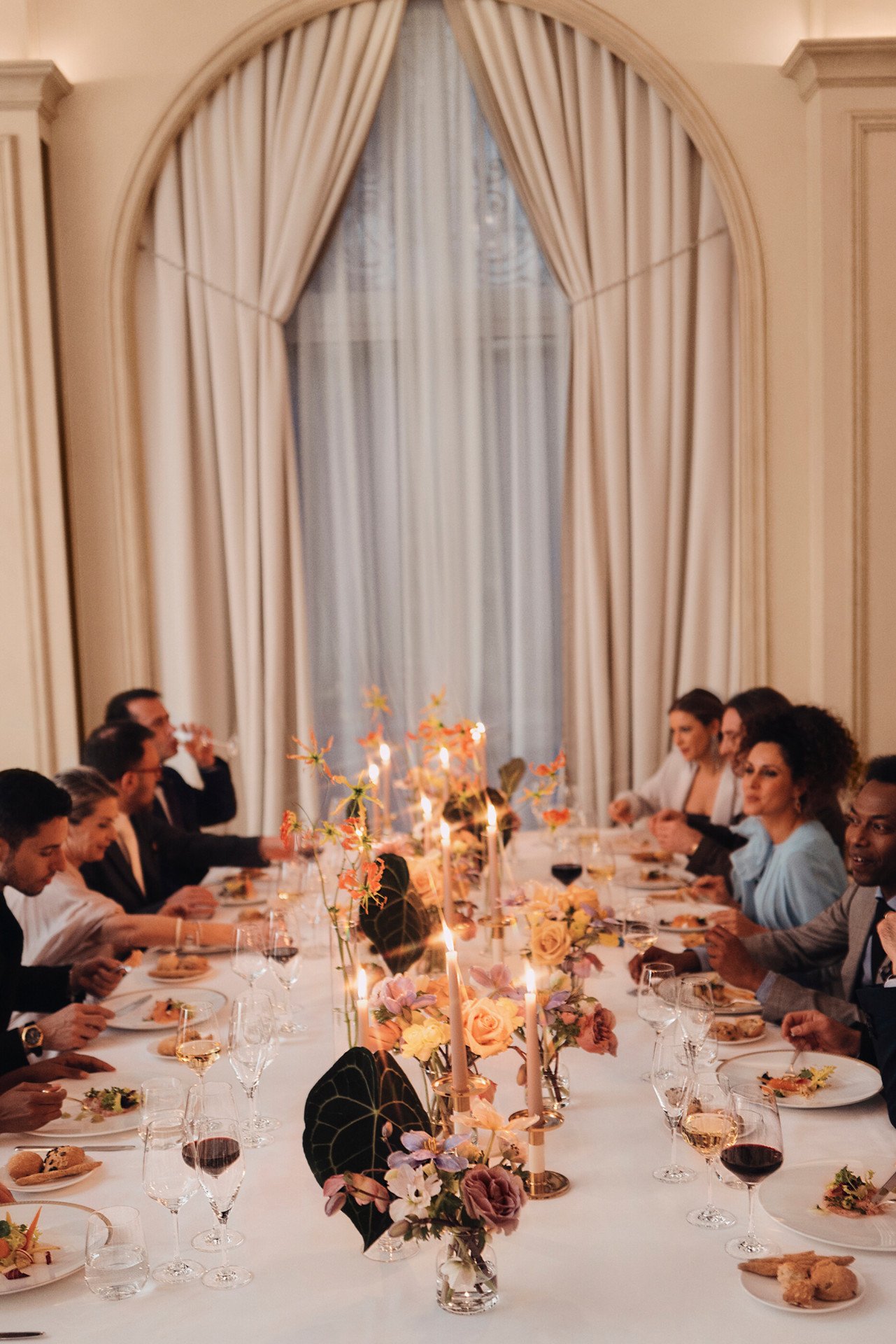 Event dinner with people seated around a table and a large window in the background