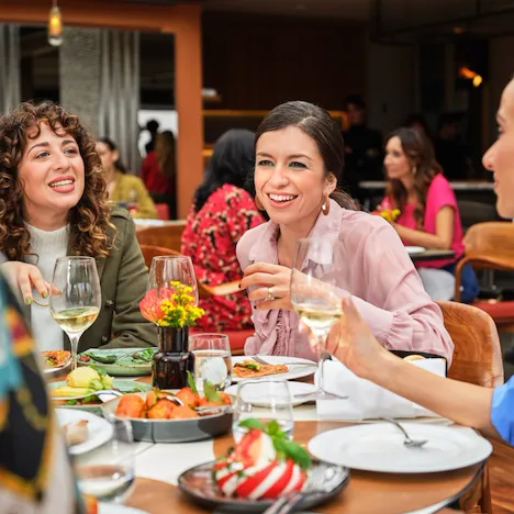 Tre donne sorridente sedute ad un tavolo de Il Giardino Ristorante a Hotel Eden Roma