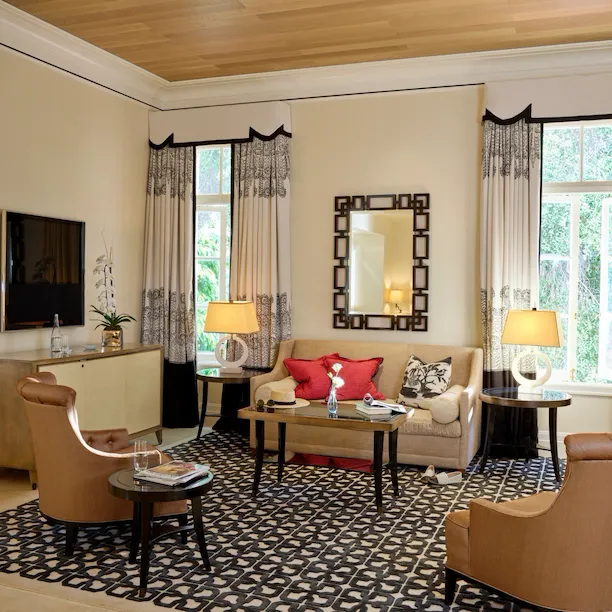 The spacious living room area of a two bedroom Bel-Air Suite featuring the coffee table, sofa, two side chairs, and TV.