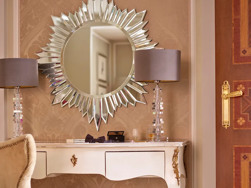 Mobile postazione trucco con uno specchio e delle lampade di design e un paio di scarpe lilla sul pavimento della Principe Suite