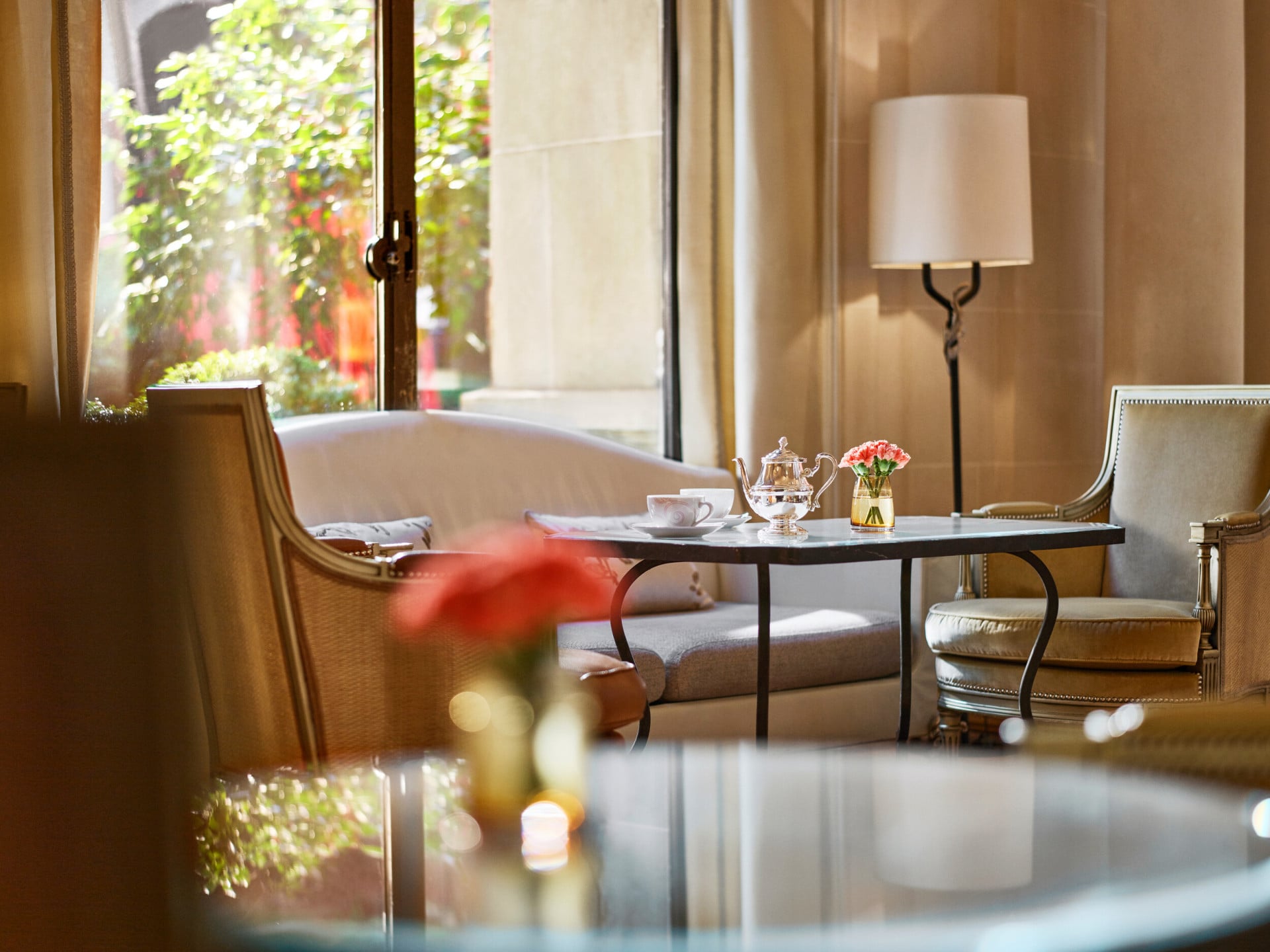 Gros plan d'une table à manger à la galerie, table avec tasses de thé, deux fauteuils et un canapé près d'une fenêtre ensoleillée, à l'hôtel Plaza Athénée, Paris
