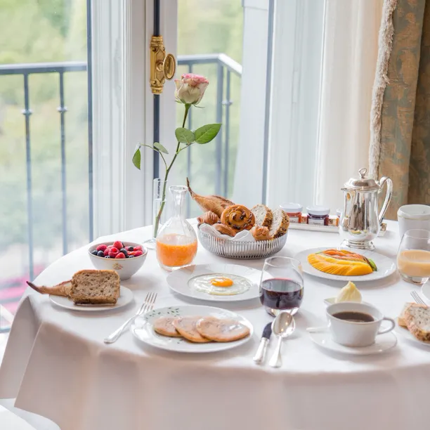 Room service table with breakfast food such as eggs, berries, fruit and pastry basket. At Le Meurice, Paris.