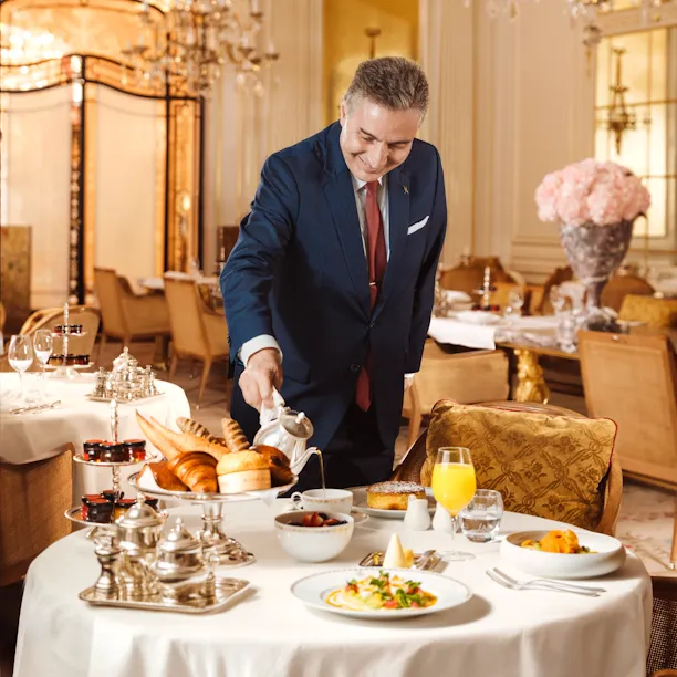 A waiter is pouring coffee in a cup for the brunch at Hotel Plaza Athénée