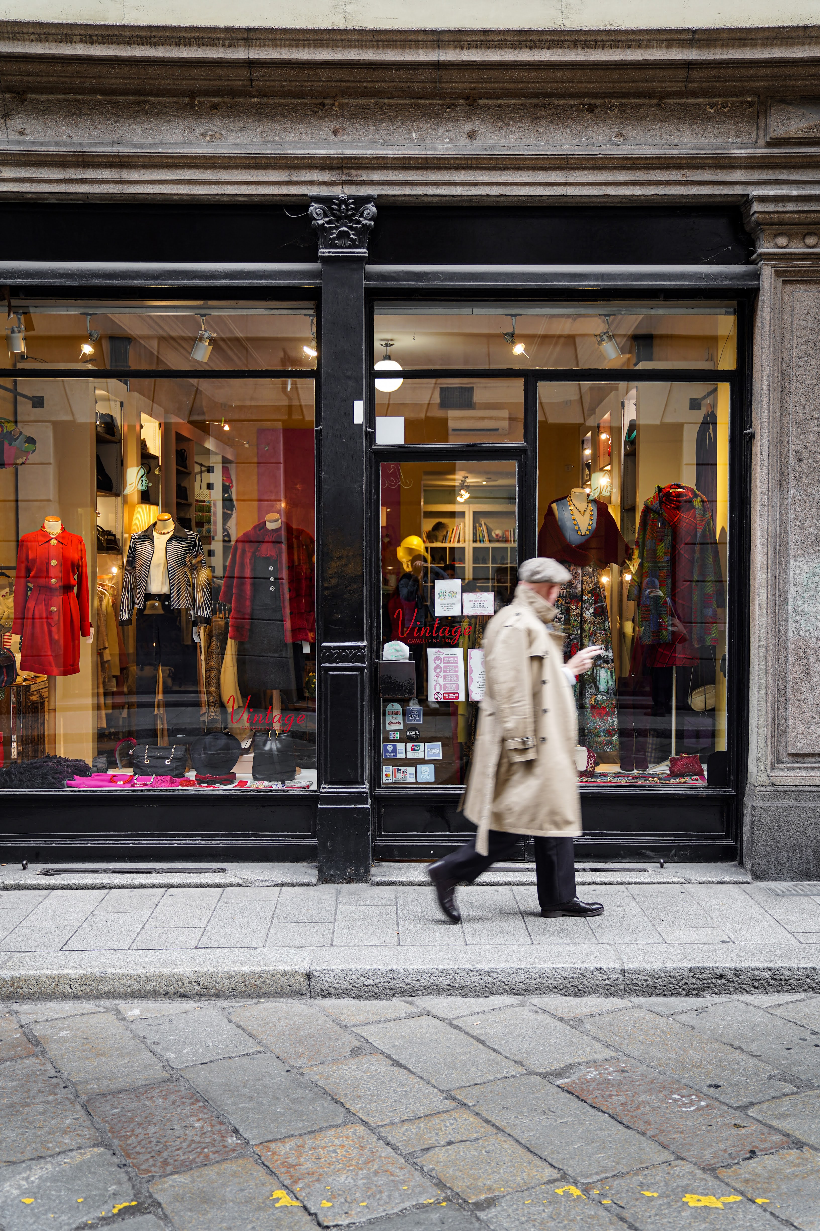 vetrina di Cavalli e Nastri, uno dei negozi vintage più celebri di Milano, con un uomo che passeggia davanti con un impermeabile beige
