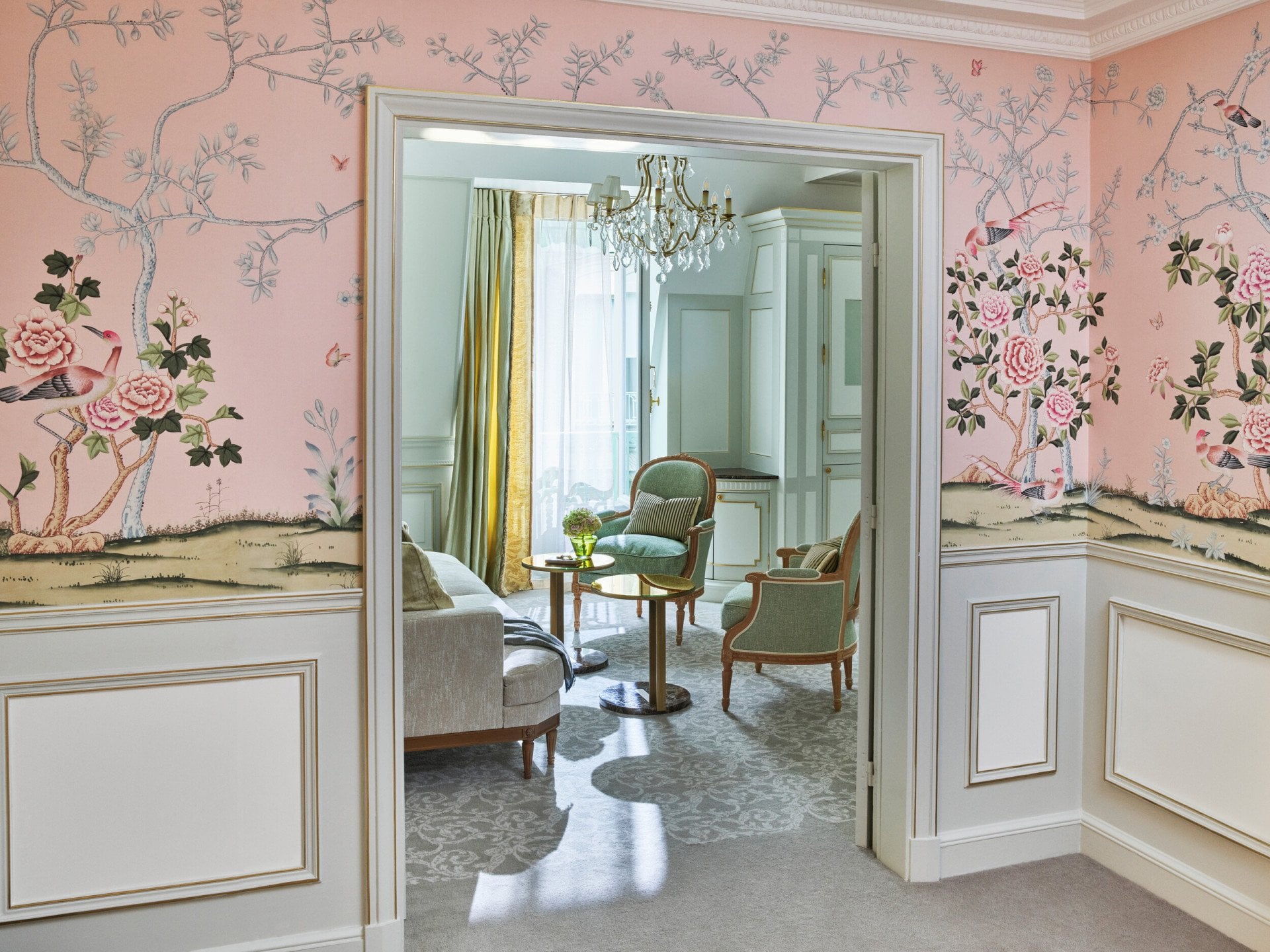 Fotografia ao longe da sala de estar, realçando o papel de parede cor-de-rosa da sala, no Le Meurice, Paris.