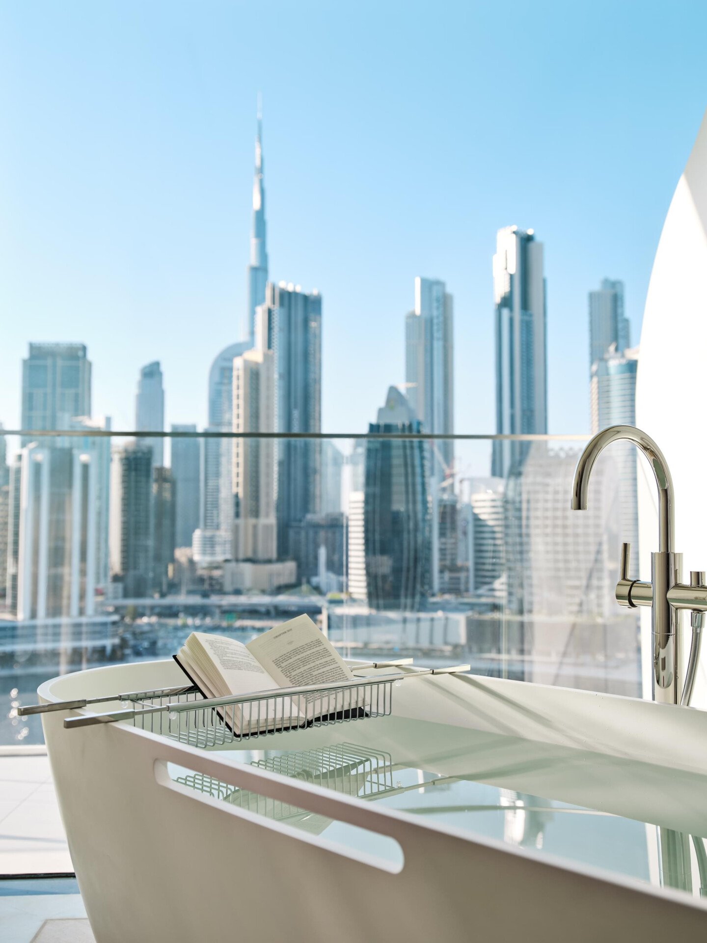 The suite's bathtub with a book placed in the stand with Dubai's skyline in the background