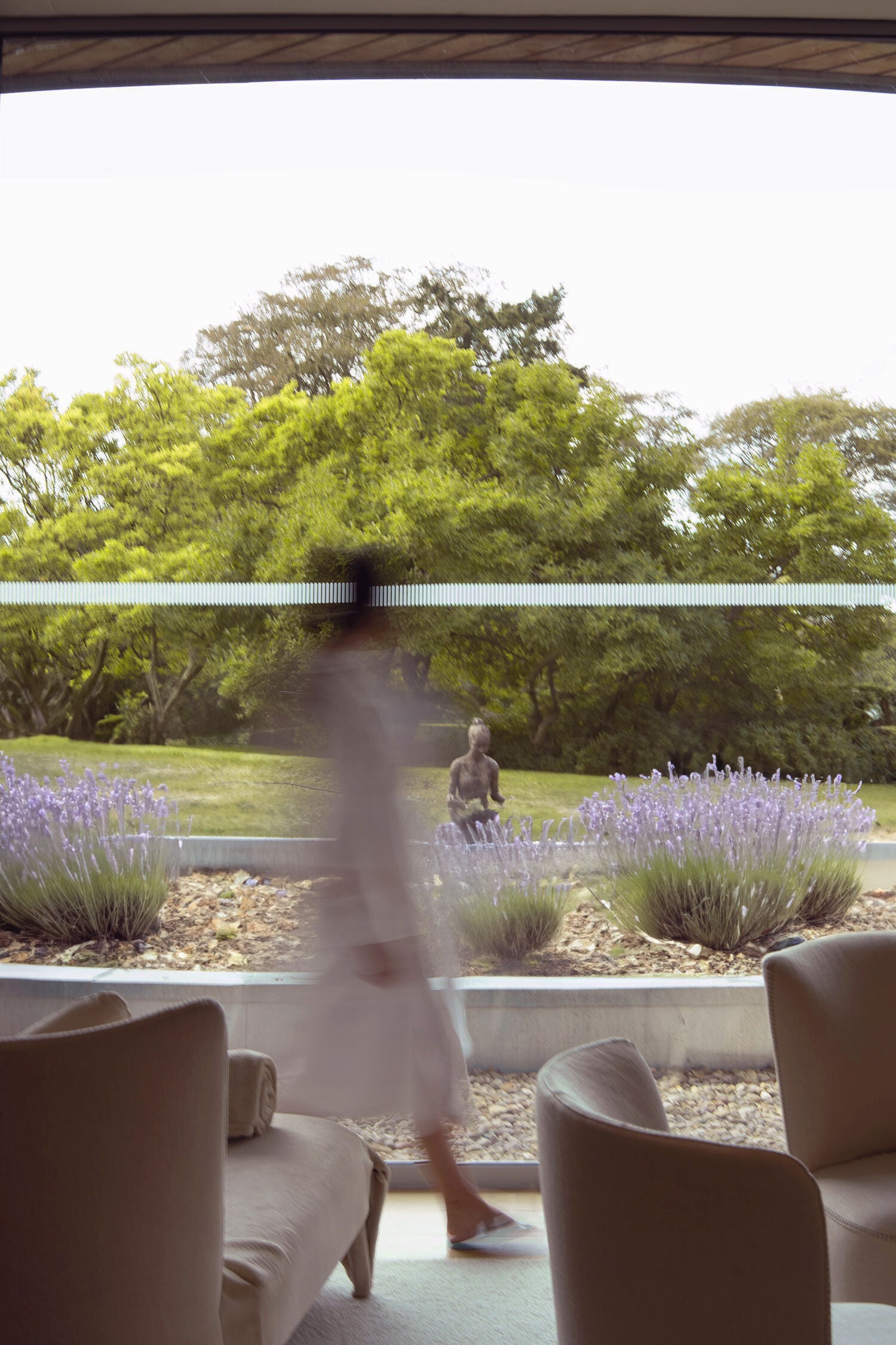 Guest in a robe walking past the wellness lounger with lavender garden in the background at The Spa at Coworth Park