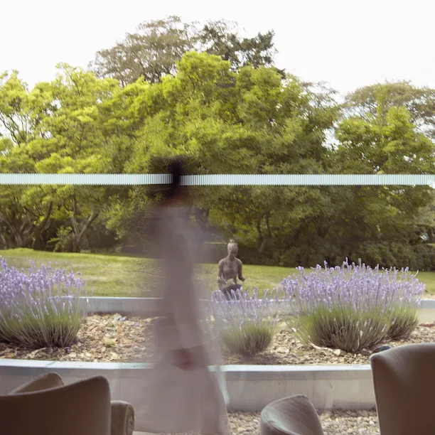 Guest in a robe walking past the wellness lounger with lavender garden in the background at The Spa at Coworth Park