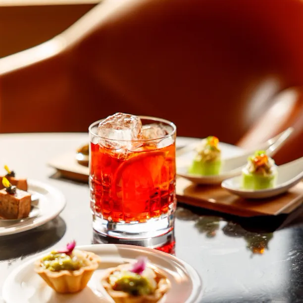 Bicchiere di negroni e selezione di tartine da aperitivo su un tavolo a Il Giardino Bar