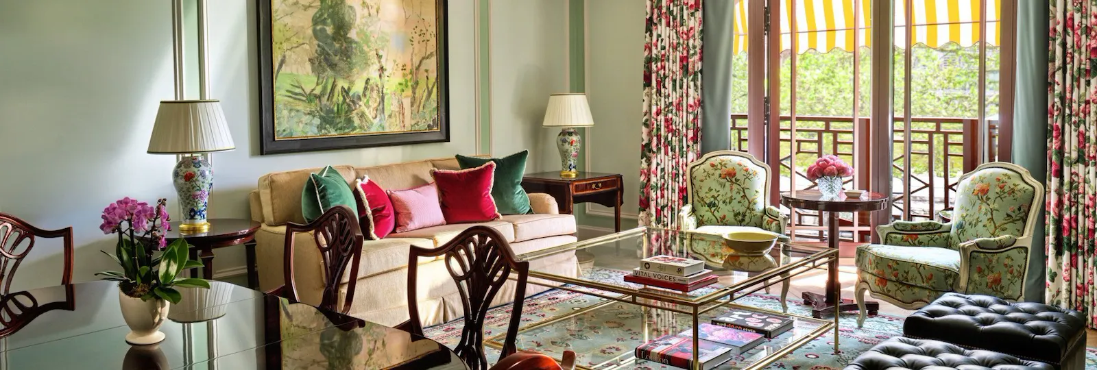 The Belgravia Suite with elegant green and red tones, a comfortable lounge seating area, dining space and a Juliet balcony offering views across Hyde Park and Park Lane.