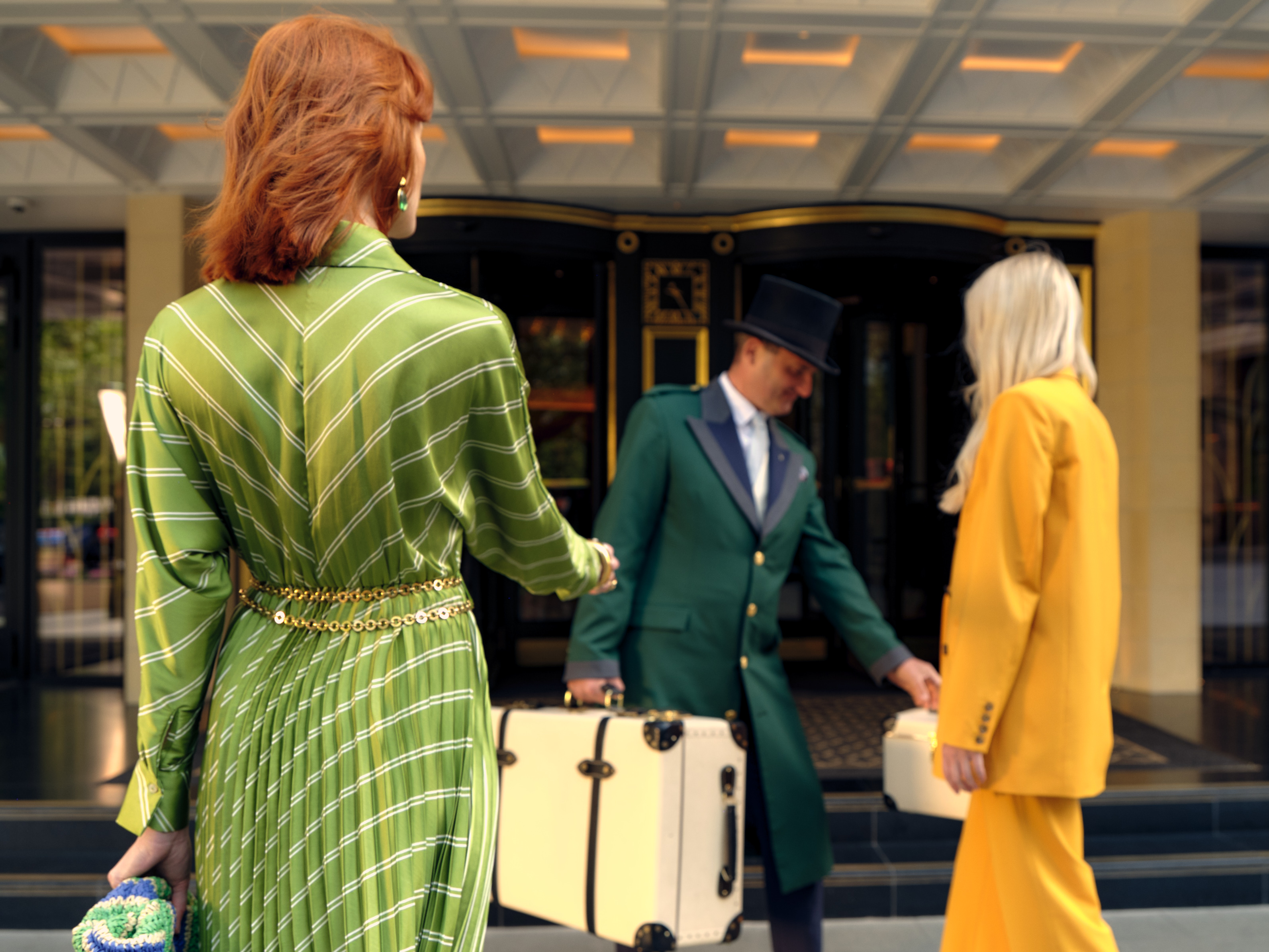 Doorman collecting luggage from hotel guests on forecourt