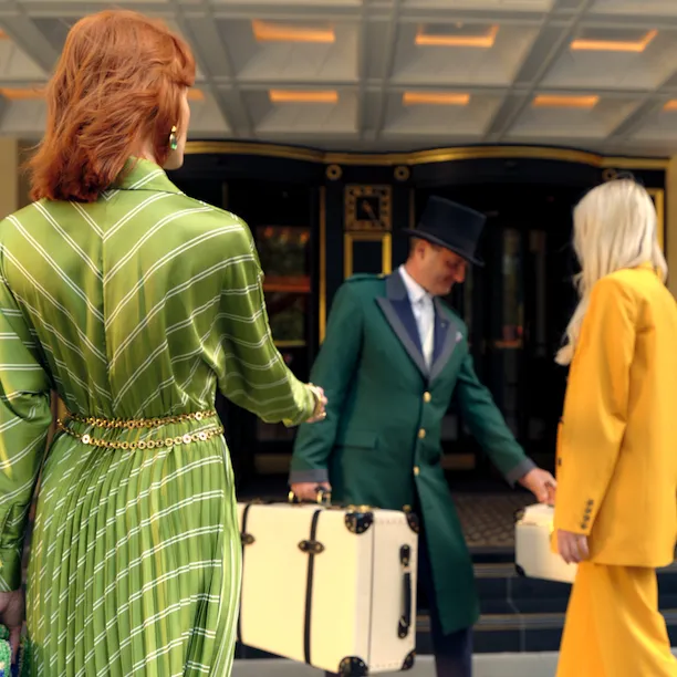 Doorman collecting luggage from hotel guests on forecourt