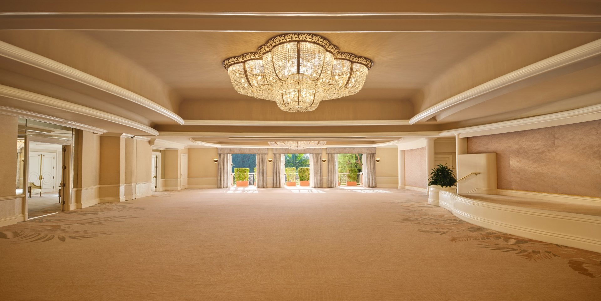 Elegant, empty banquet hall with chandelier and large windows, calm and grand setting