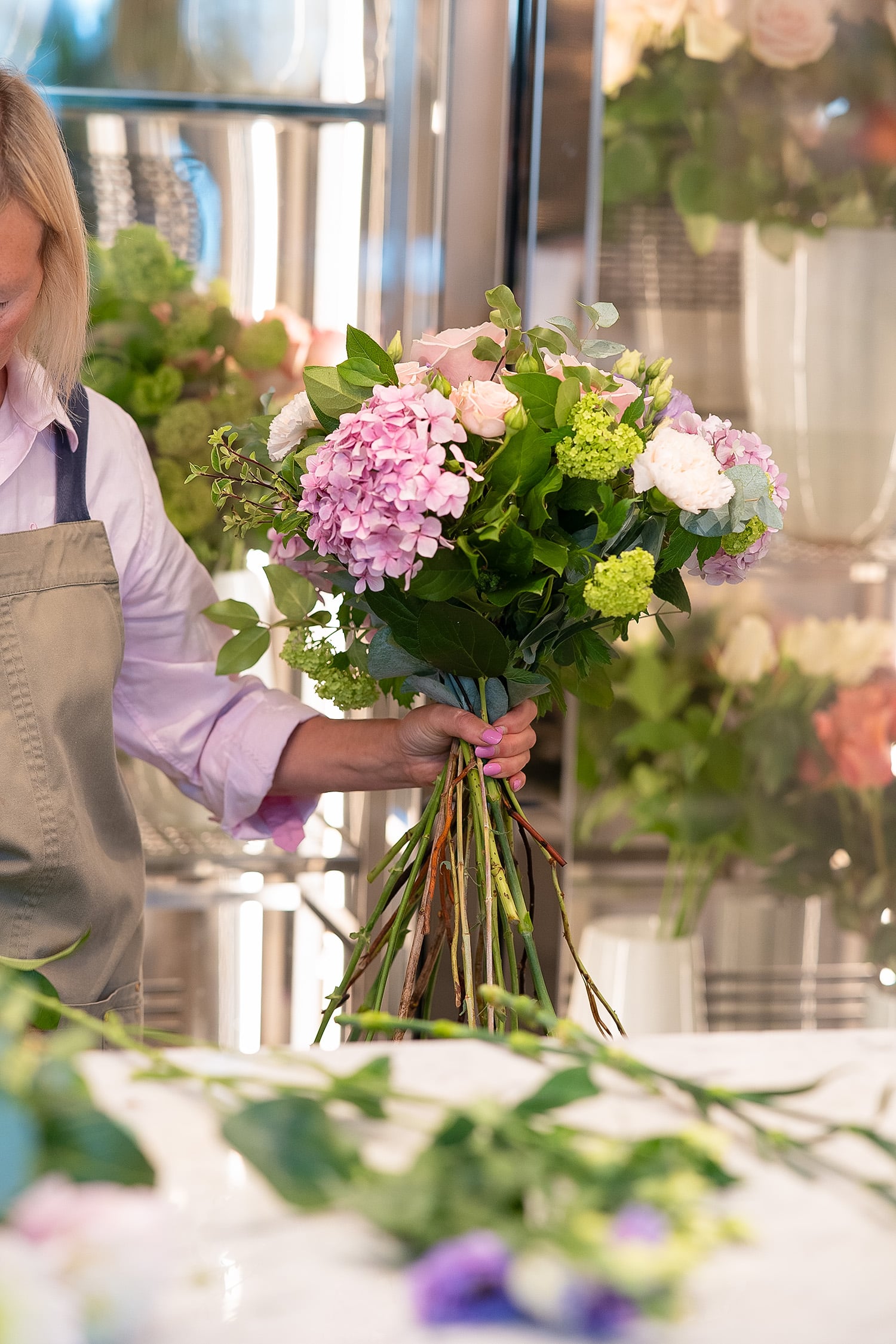Florist assembling a pink floral bouquet with roses and hydrangeas at Cake & Flowers boutique