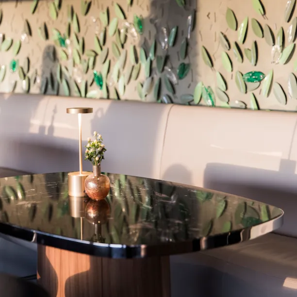 Angolo de Il Giardino bar con parete decorata con foglie di vetro e metallo e tavolo di marmo