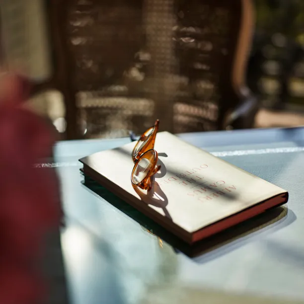 A book and a glass on a table with a sunlit background