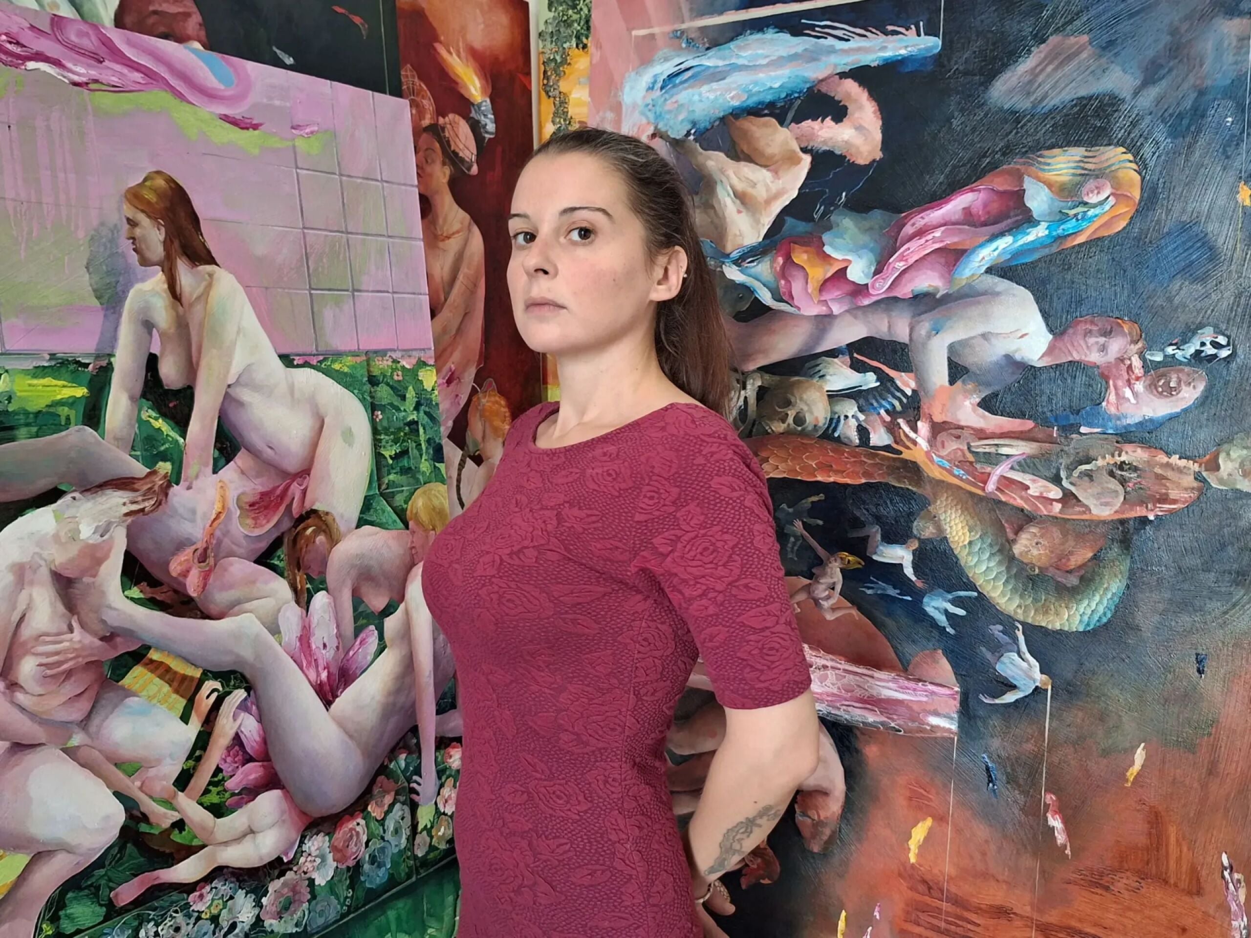 Artist Chiara Sorgato standing in front of some of her paintings