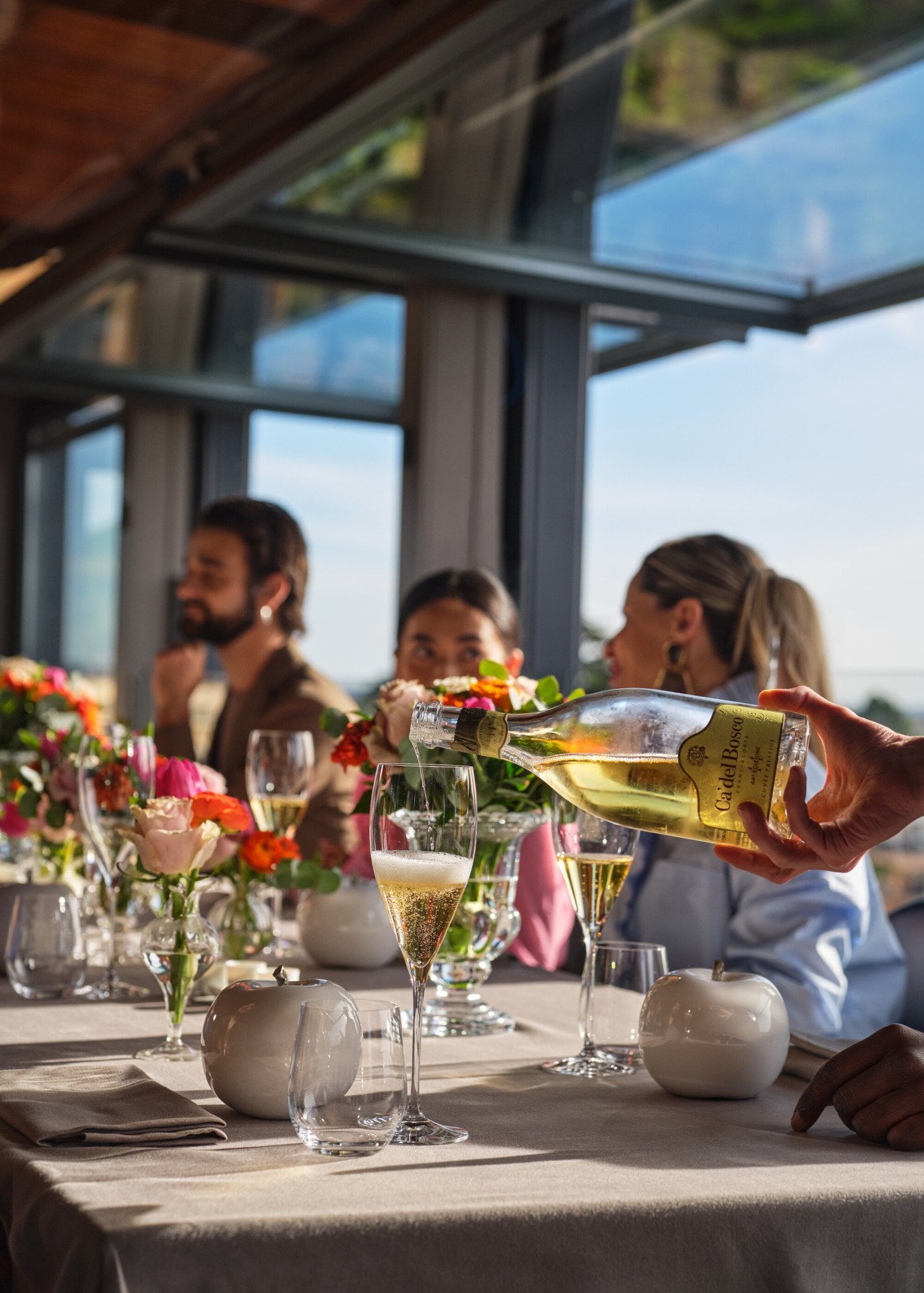 Un cameriere versa un flute di prosecco su una tavolata