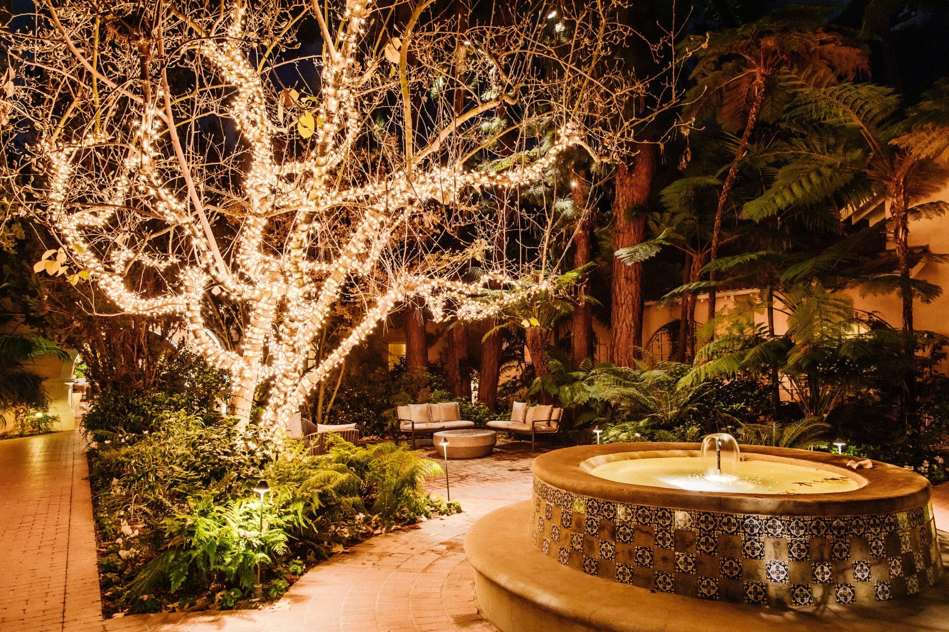 Central courtyard during festive season with string lights covering the tree above the fountain at Hotel Bel-Air. 