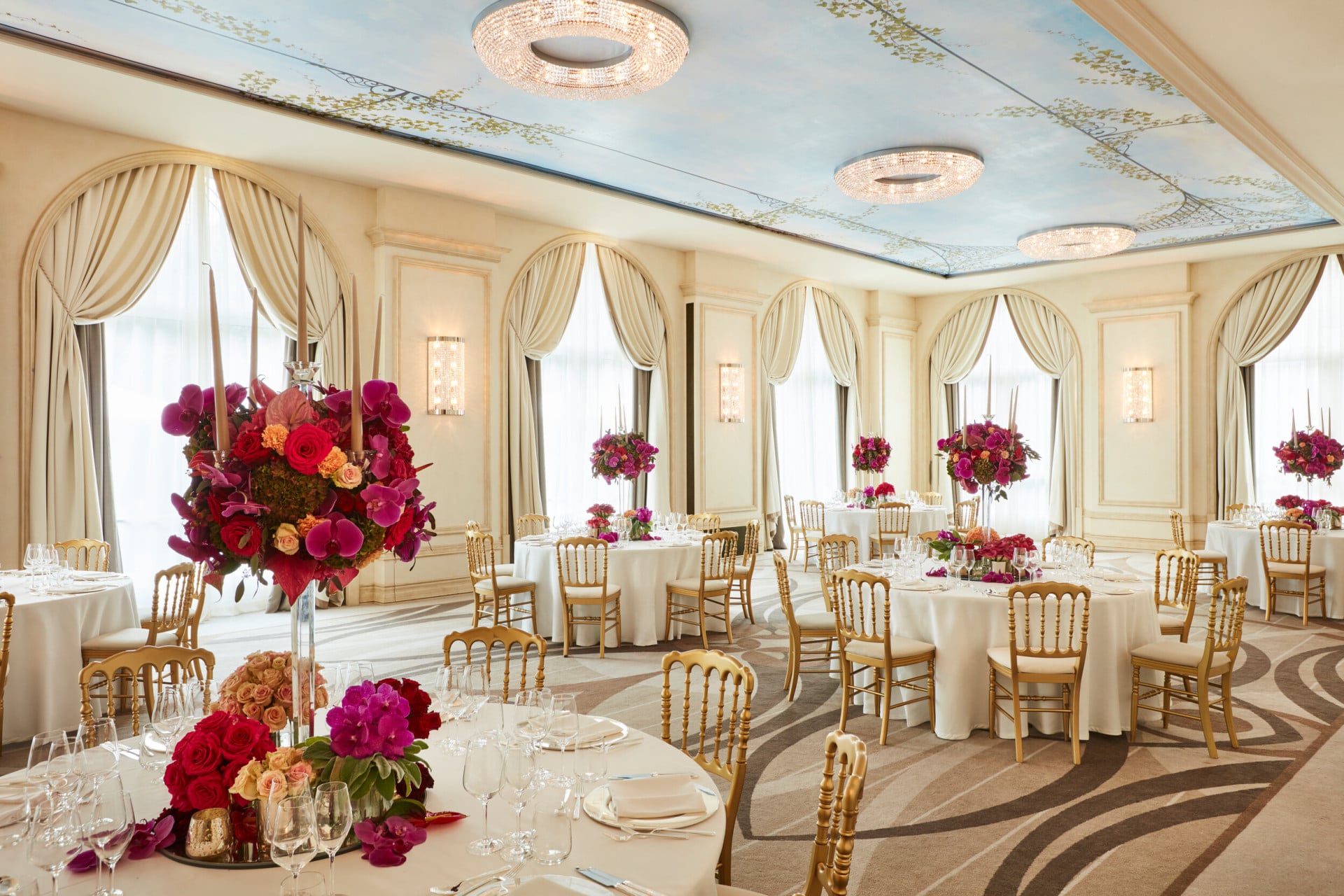 'Veranda' meeting room with gala dinner set up. Every round table has important centerepiece with pink flowers and candles.
