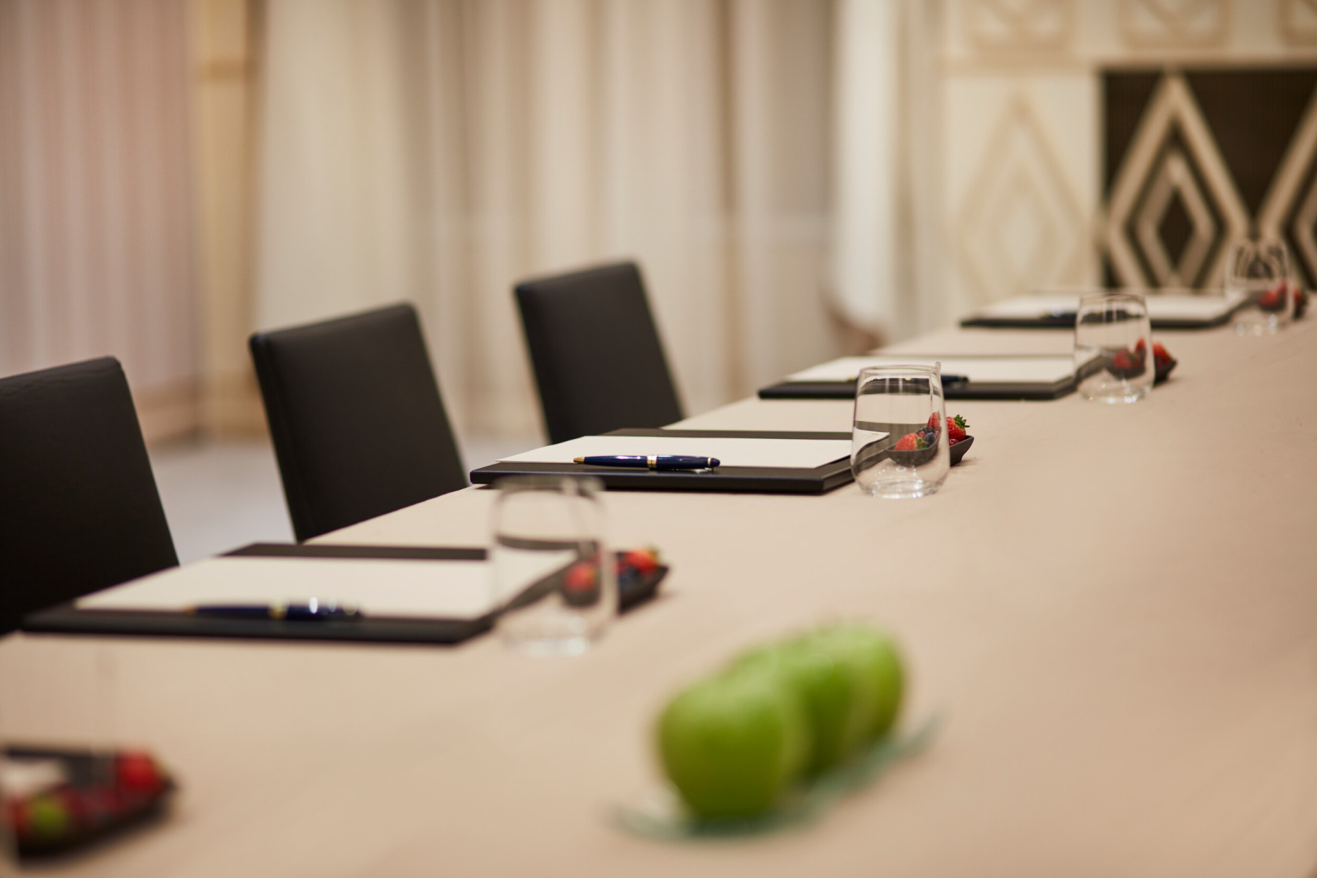 Close up of a table in 'Galilei' meeting room with notepads, pens, waters and fruits.
