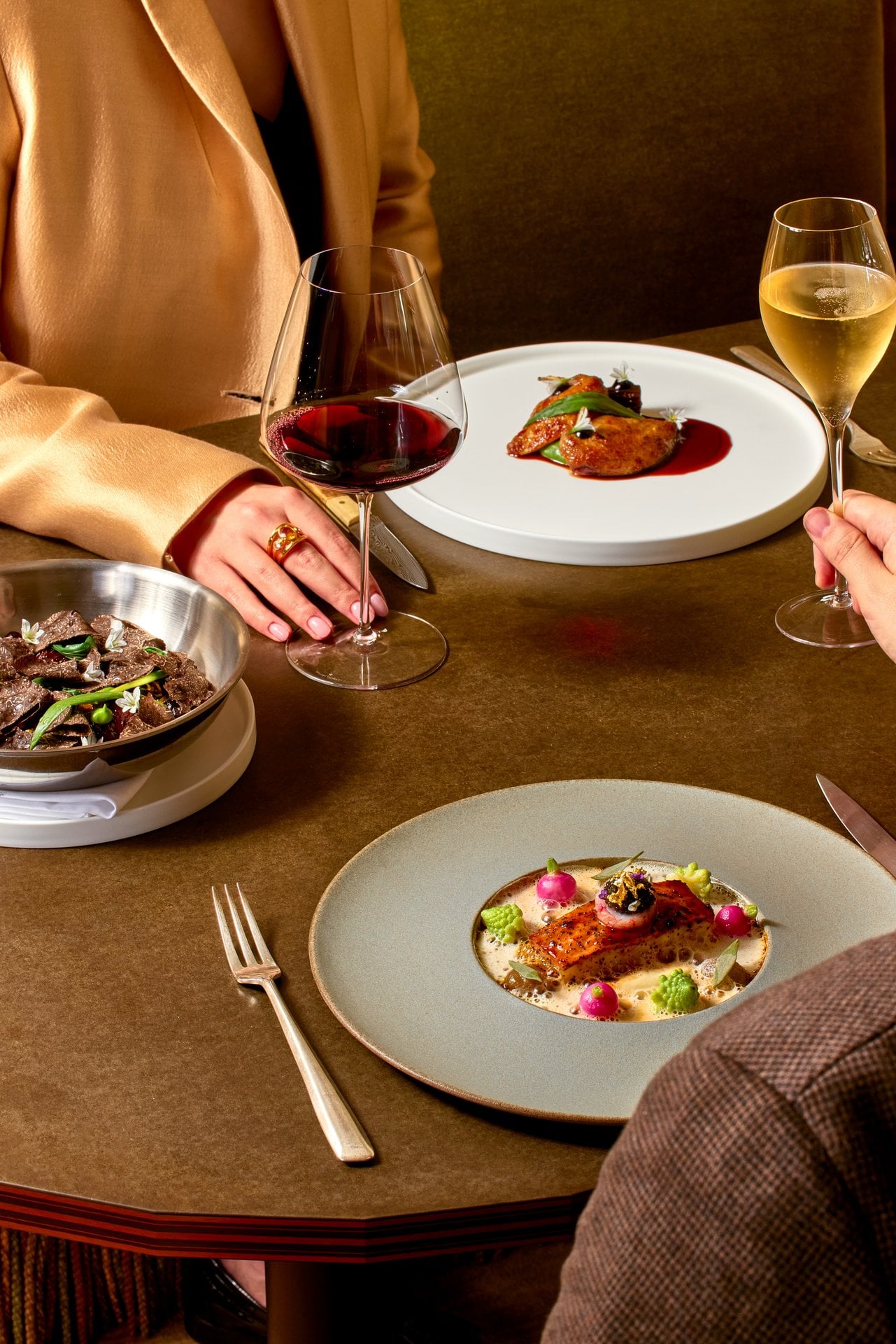 People enjoying a dinner with wine and elegantly plated dishes at a cozy restaurant table