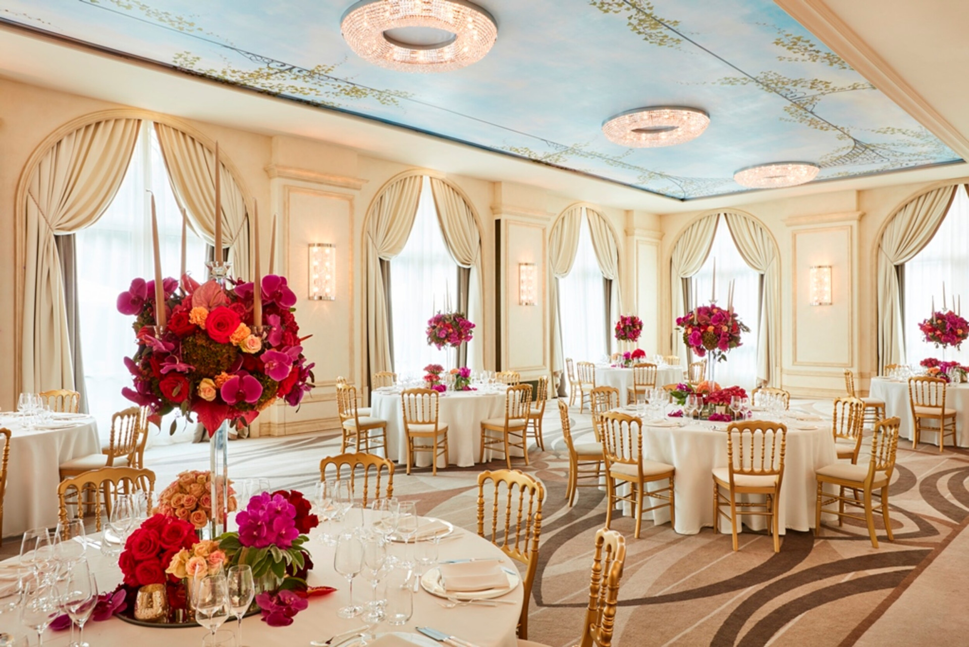 'Veranda' meeting room with gala dinner set up. Every round table has important centerepiece with pink flowers and candles.