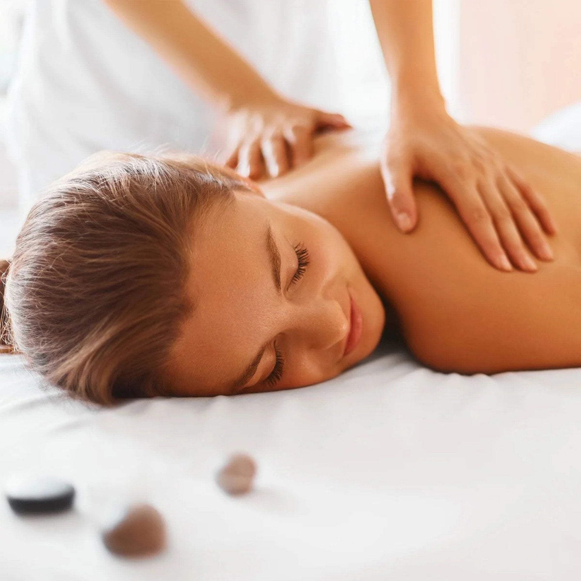 Picture of a woman lying on a message table while someone is massaging her back