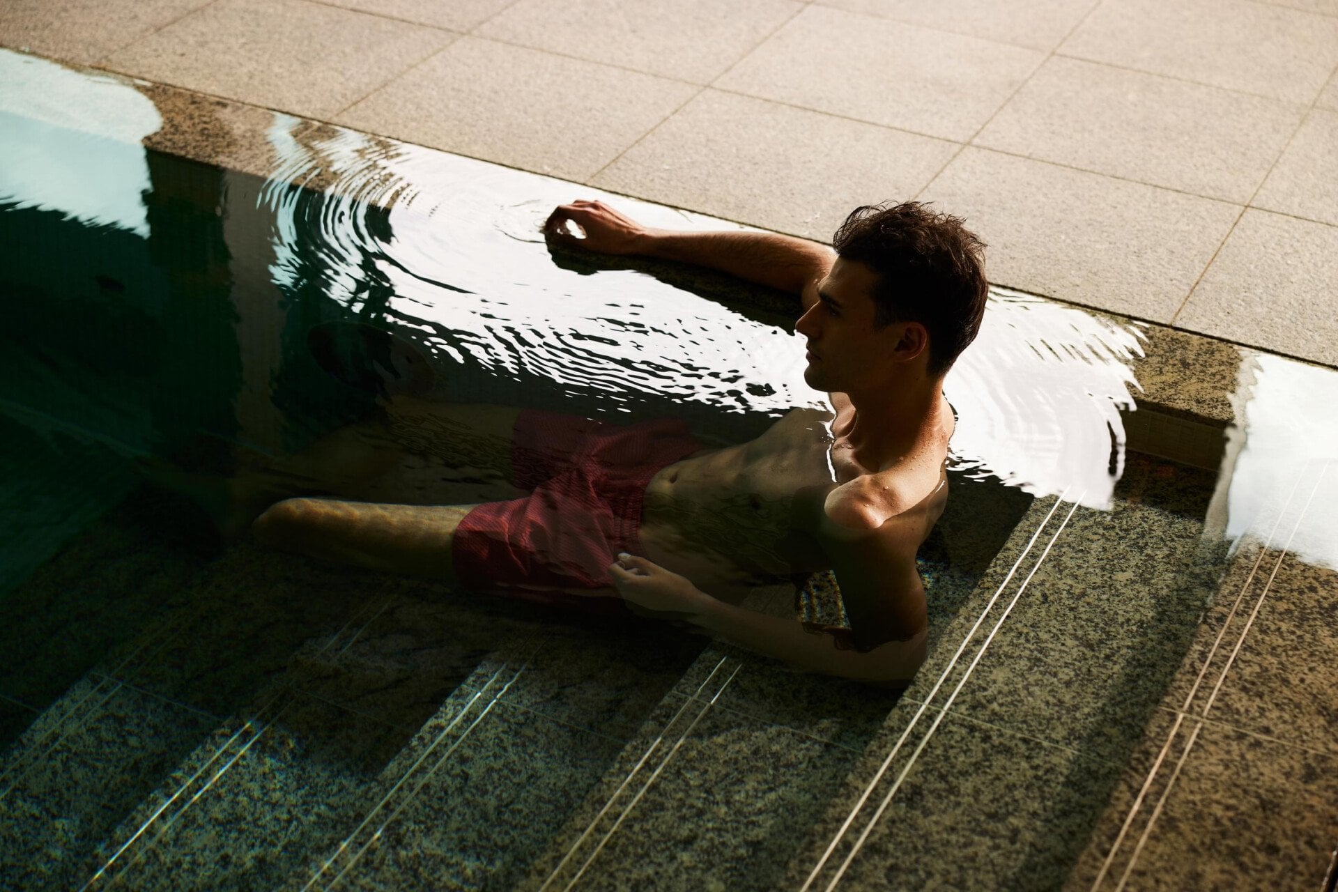 Guests enjoying the pool at Coworth Park with beautfiul light flooding through the open doors to the lush green forest and hills 