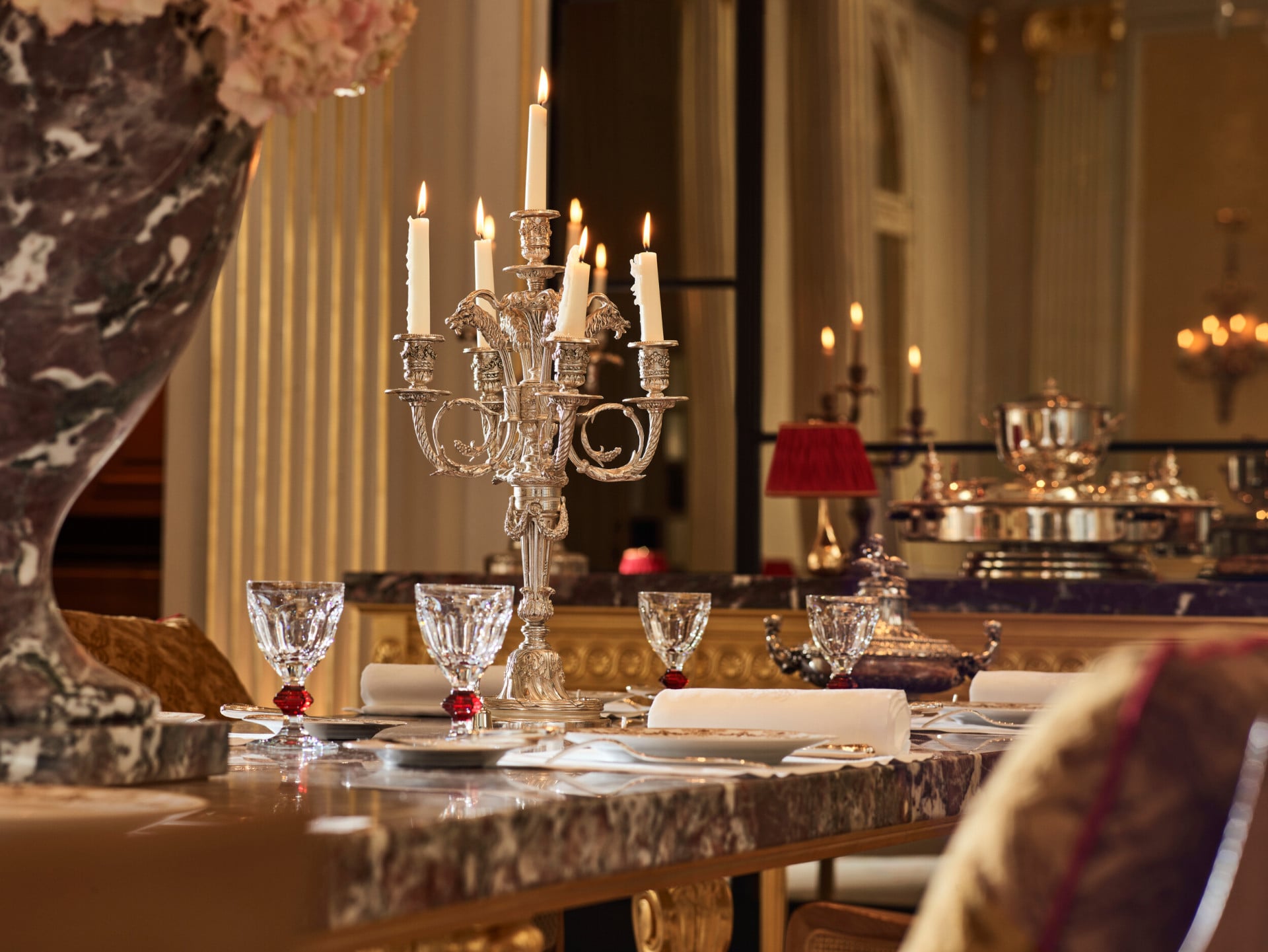 Marble table of the Jean Imbert au Plaza Athénée dining room, drawned up with crystal glasses and silver candleholder. At Hotel Plaza Athénée Paris.