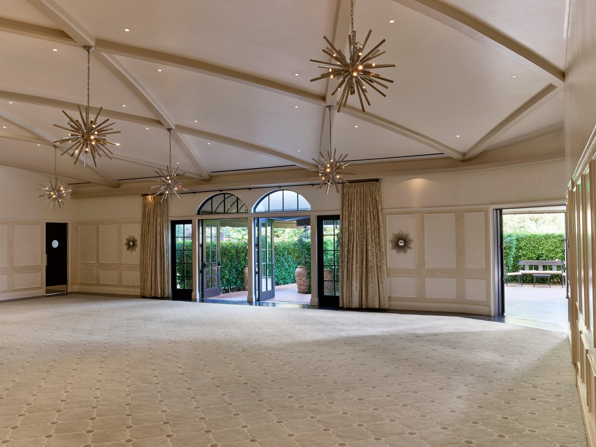 Garden Ballroom event space at Hotel Bel-Air with star-shaped chandeliers across the ceiling and natural light from the entrance doors. 