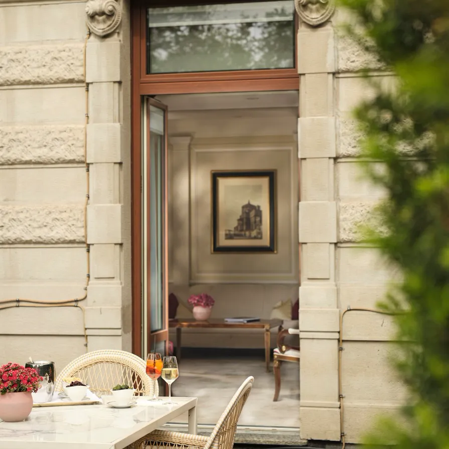 Vista della Principe Suite dalla Terrazza, in primo piano il tavolo in marmo con un aperitivo, sullo sfondo dettagli di design della suite