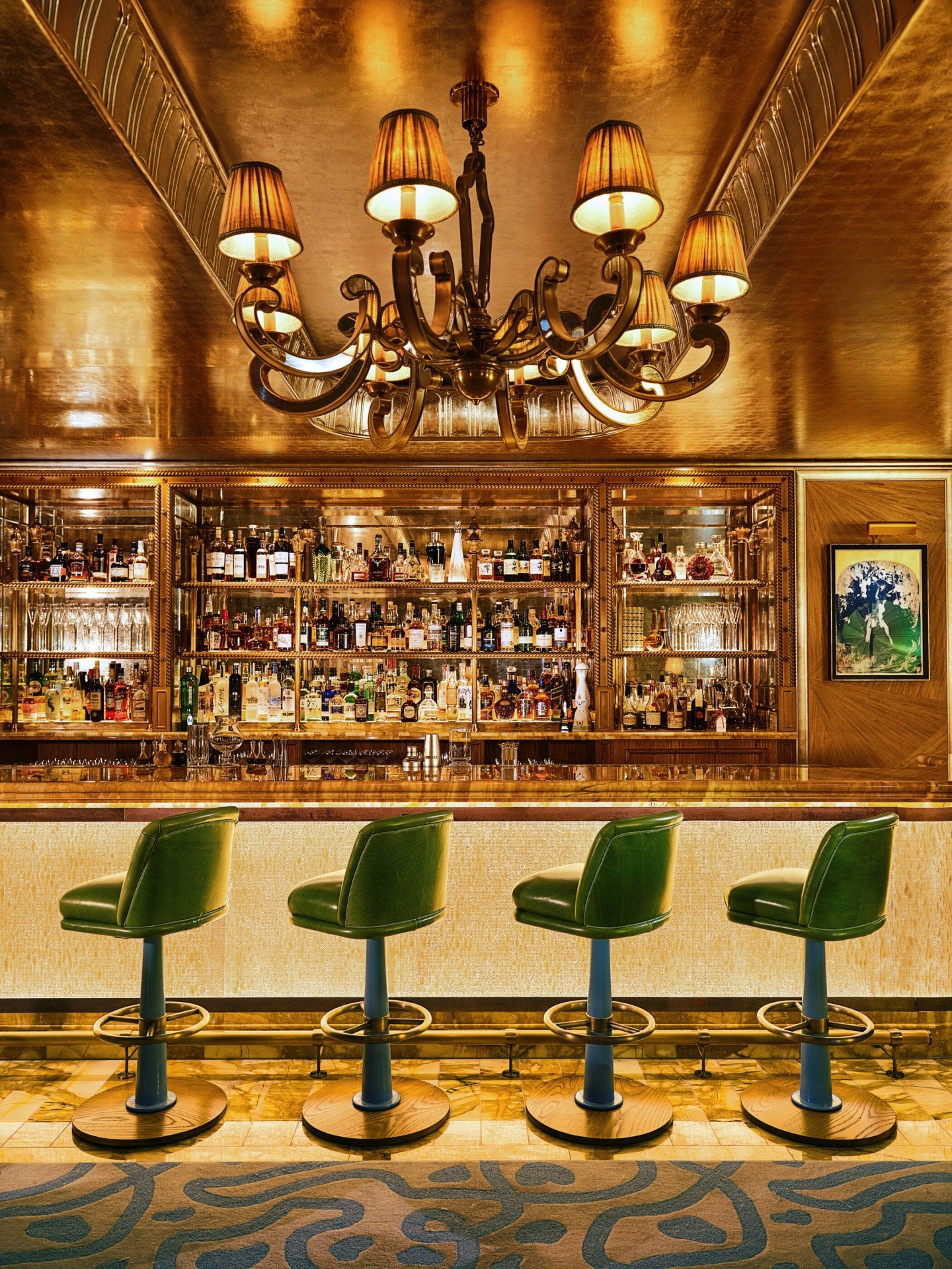 The Vesper Bar at The Dorchester, showcasing a marble bar, green stools, and warm golden interiors.
