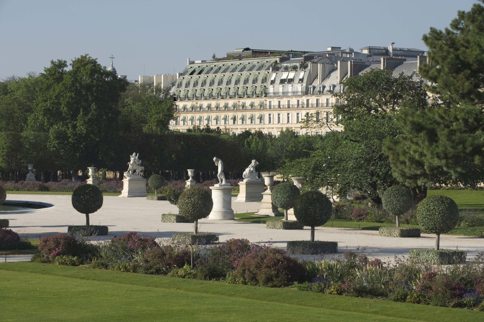 Vue lointaine de l’hôtel du point de vue du jardin des Tuileries, montrant la partie supérieure de la façade et les tons verts, au jardin des Tuileries, Paris.