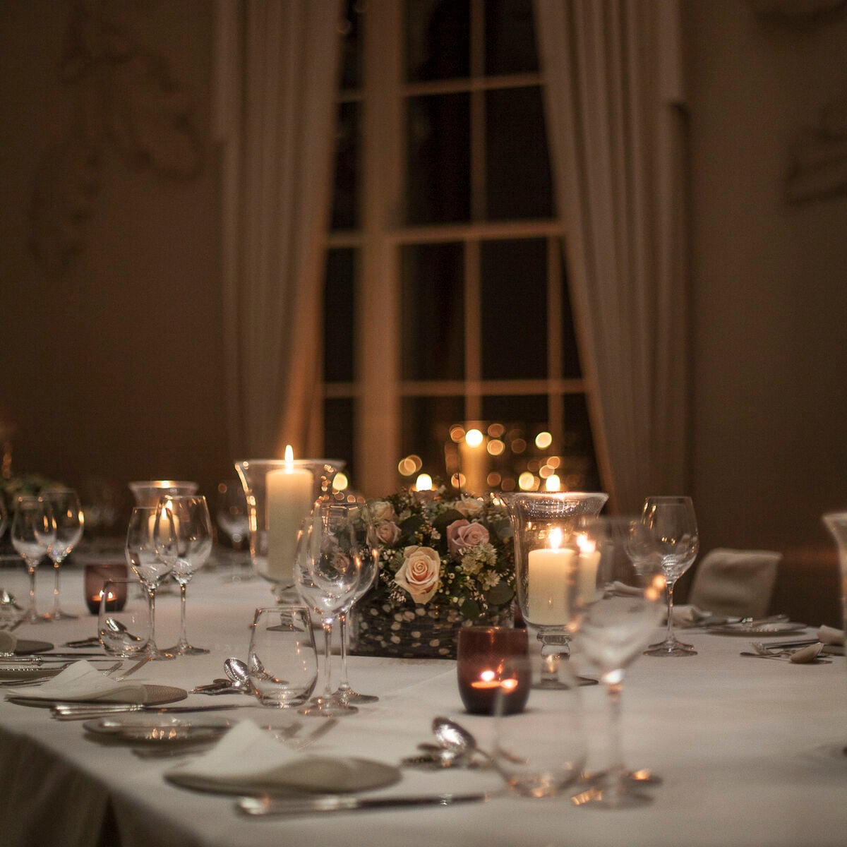 Candlelit dinner table with rose centrepiece set for an evening event at Coworth Park